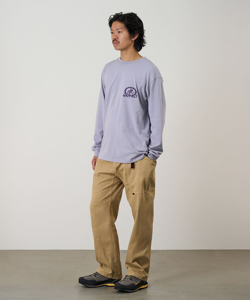 Model wearing a lavender Gramicci Equipped For Dirt L/S Tee with a a Gramicci gear graphic graphic and olive shorts on a light tone background.
