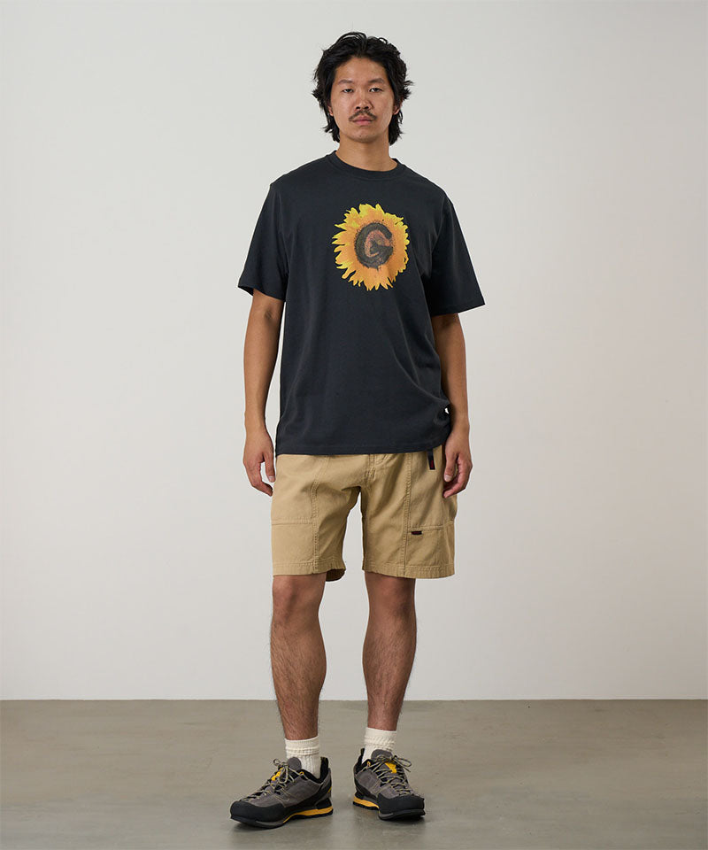 Model wearing a vintage black Gramicci G-Flower Tee with a sunflower graphic and beige shorts on a light tone background.