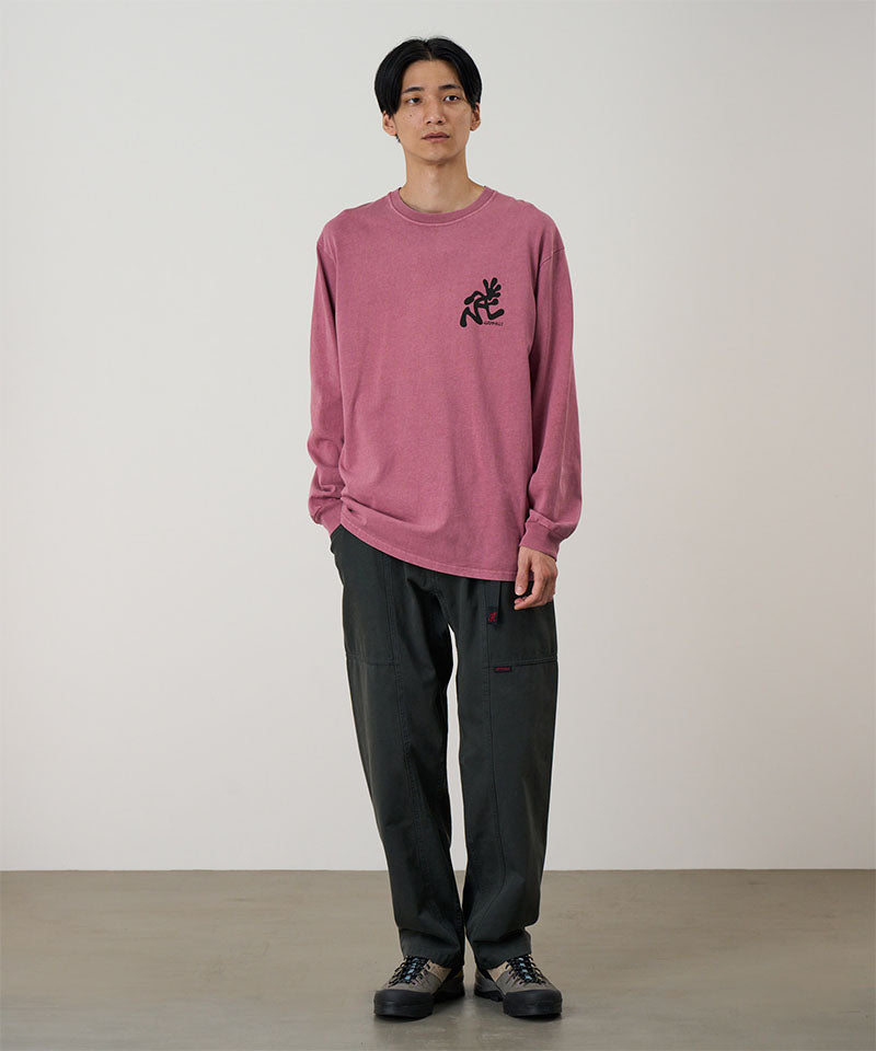 Model wearing a red pigment Gramicci Running Man L/S Tee Pigment Dyed with a black graphic and dark pants on a light-tone background.
