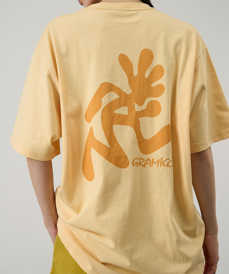 Person wearing a yellow t-shirt with a large orange graphic on the back against a gray background