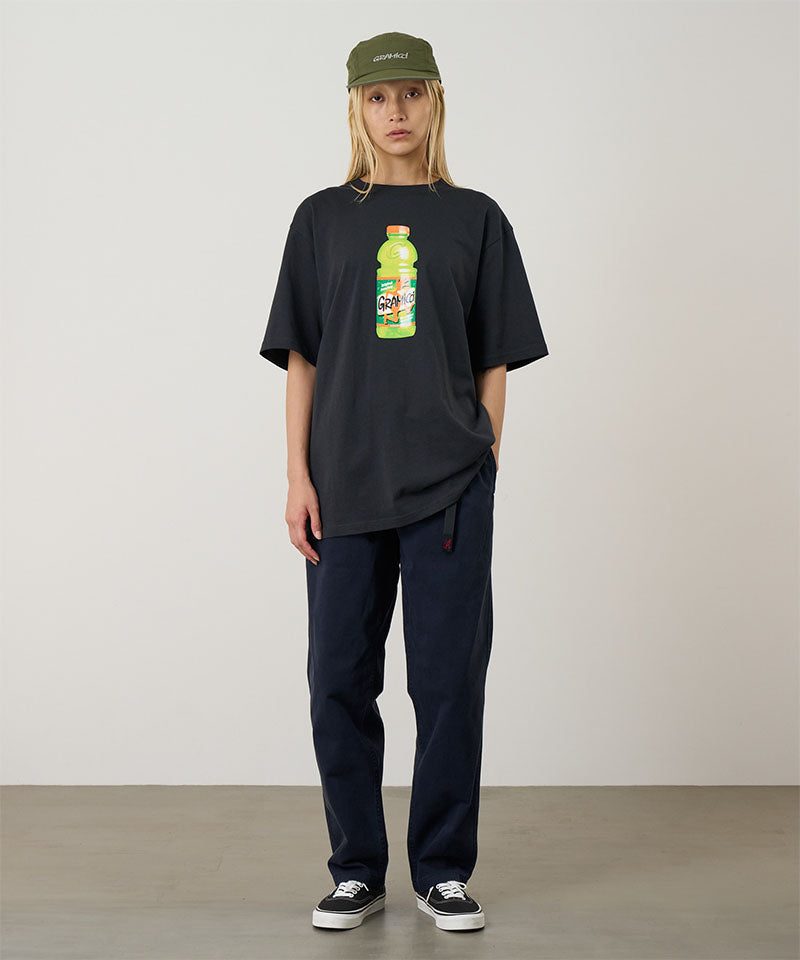 Model wearing a vintage black Gramicci Quencher Tee with a hydration drink graphic and blue pants on a light tone background.