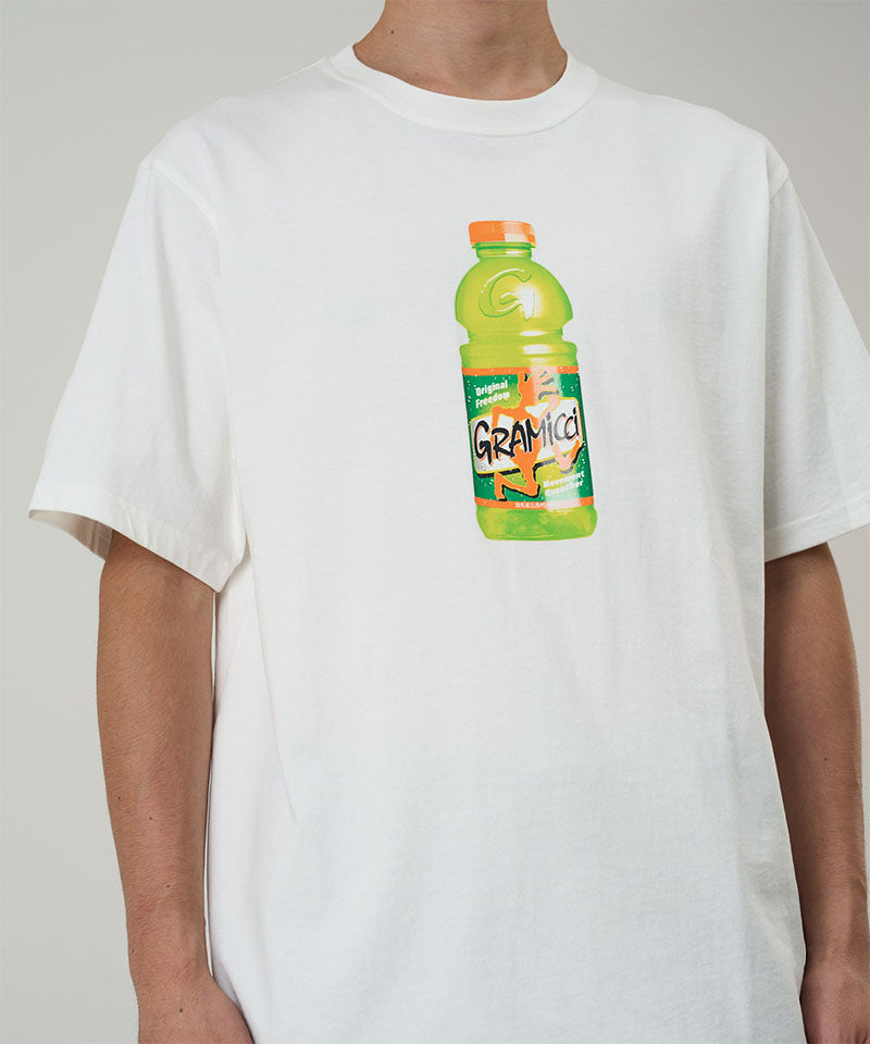 Model wearing a Gramicci white Quencher Tee with hydration drink graphic against a light tone background.