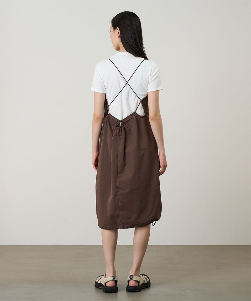 Back view of a model wearing a Gramicci Women's Woven Milton Dress in the color walnut and a white undershirt on a light-tone background.