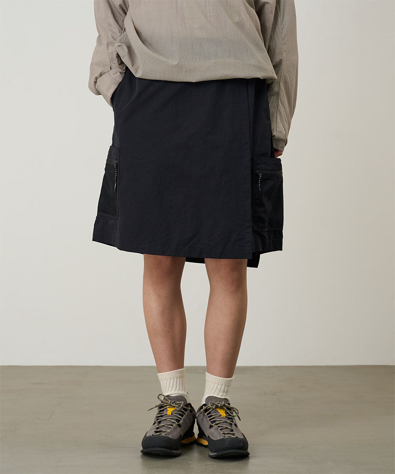 Model wearing black Gramicci Guide Skort and a beige jacket on a light-tone background.