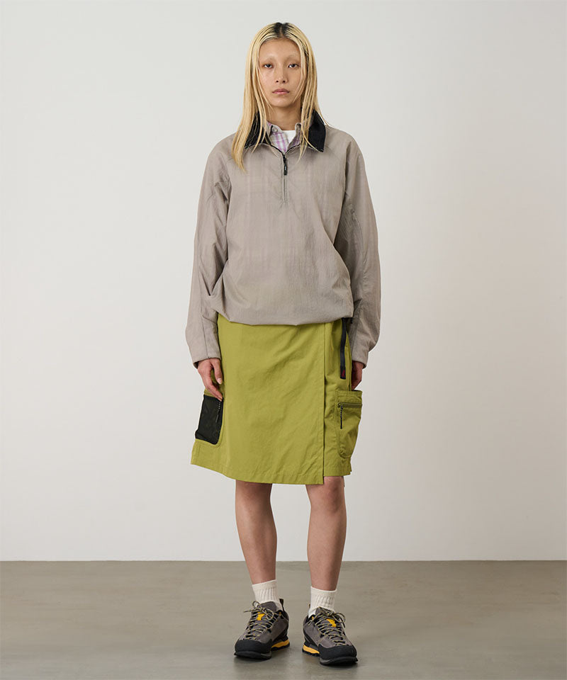 Model wearing field green Gramicci Guide Skort and a beige jacket on a light-tone background.
