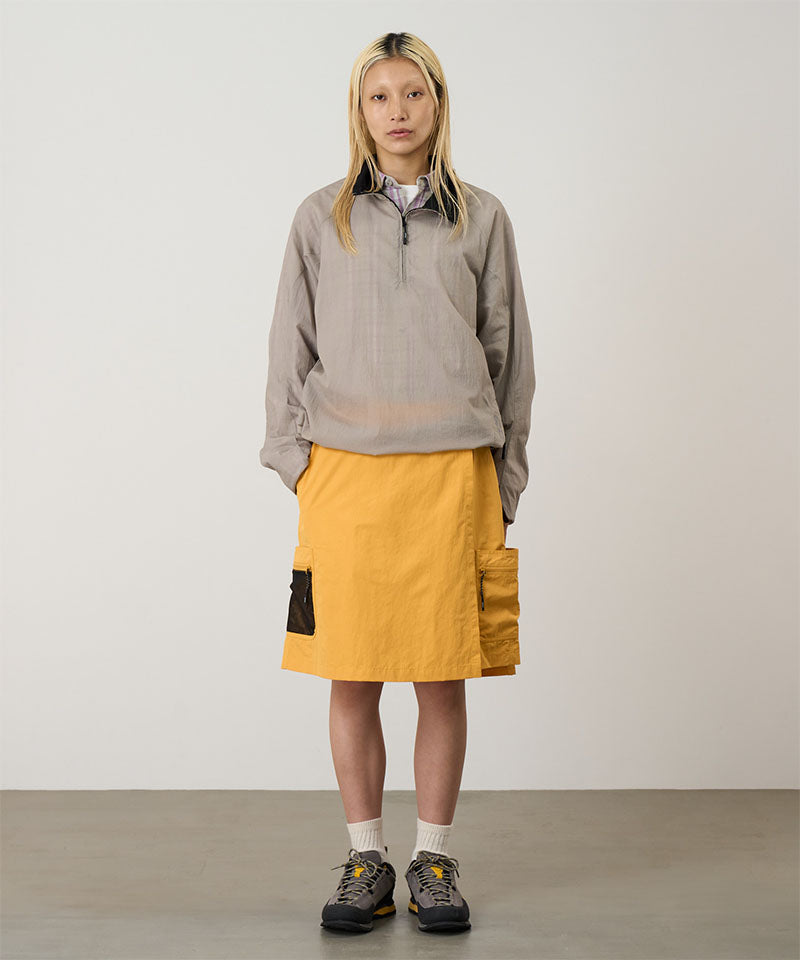 Model wearing mango colored Gramicci Guide Skort and a beige jacket on a light-tone background.