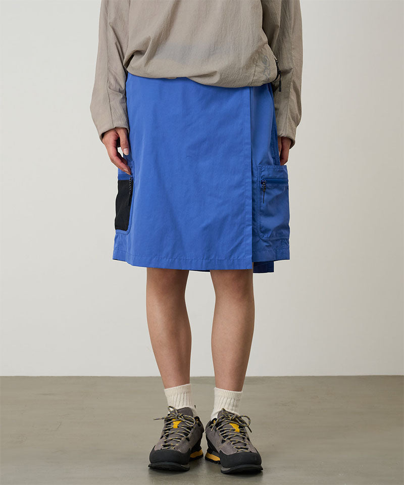 Model wearing blue Gramicci Guide Skort and a beige jacket on a light-tone background.