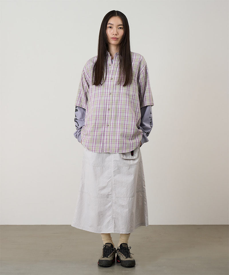 Person wearing a plaid shirt and white skirt against a plain background