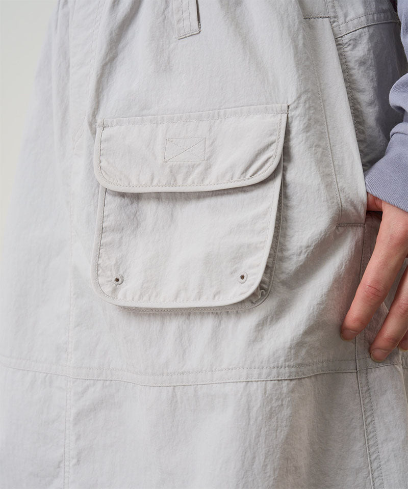 Close-up of a light gray skirt with a pocket and a hand touching it.