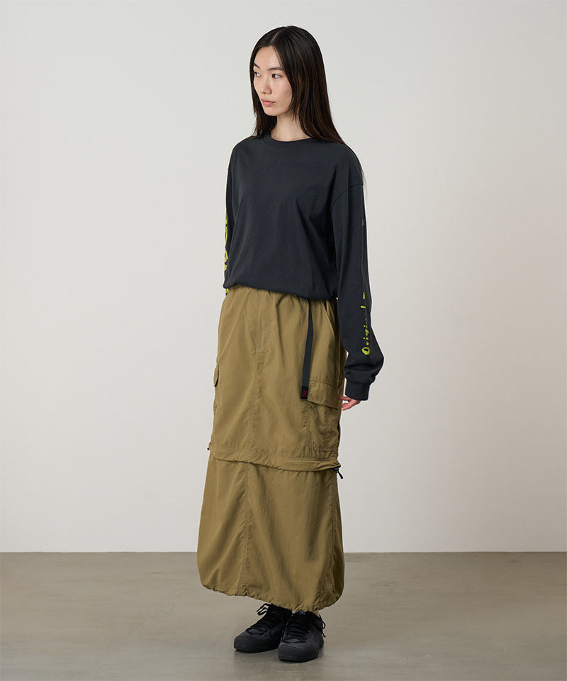 Model wearing a Gramicci Convertible Cargo Skirt in the color khaki and a black shirt on a light-tone background.