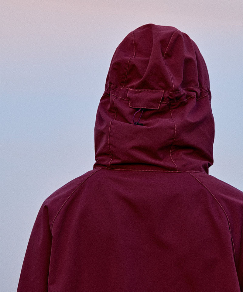 Maroon Gramicci raincoat with hood on a sky background
