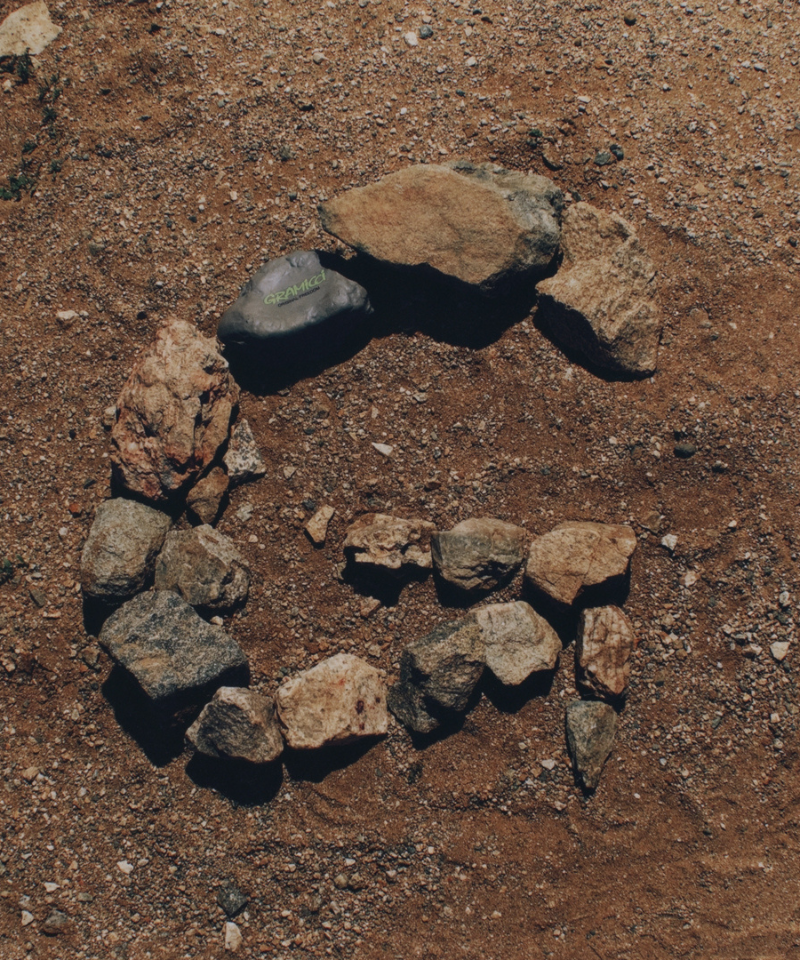 An arrangement of stones in the shape of the letter 'G' on a sandy surface.