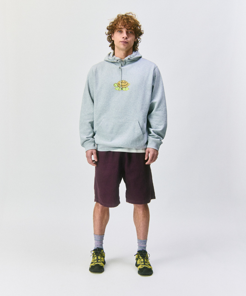 Model wearing a light gray hoodie with a turtle logo, maroon shorts, amethyst Hemp Blend Socks, and green shoes on a white background.