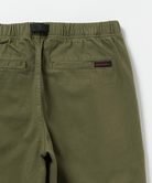 Close-up back view of olive green pants  featuring a red Gramicci logo.