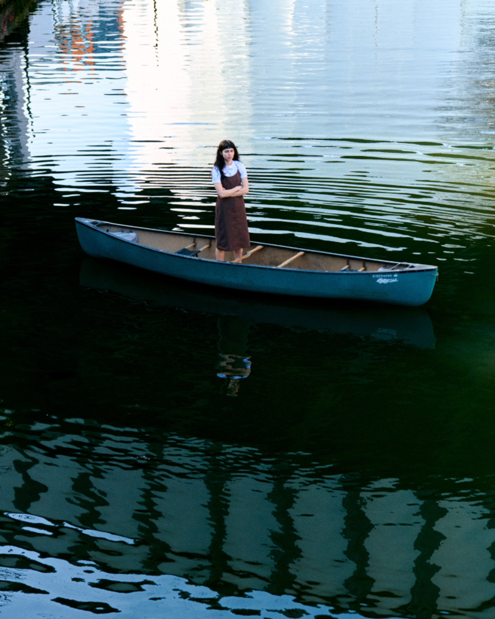 Woman standing in a canoe on a calm lake