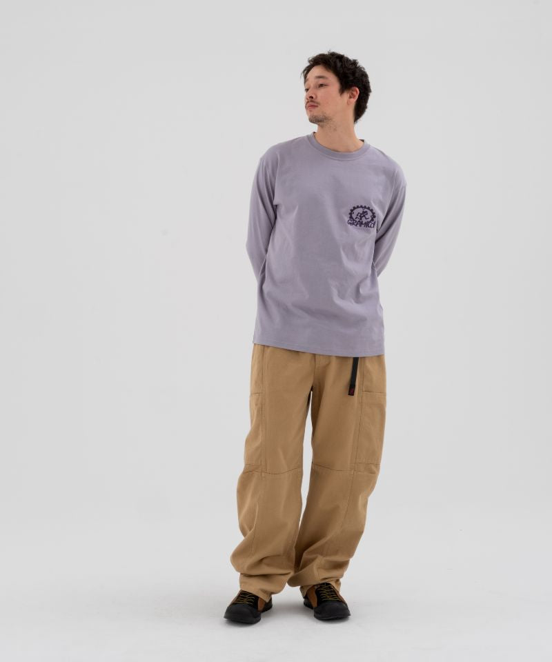 Model wearing beige Gramicci Voyager Pants and a lavender Gramicci Equipped Dirt Long-Sleeve-Tee on a light-tone background.