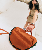 Model wearing a beige dress holding an orange Gamicci Multi Side Bag.