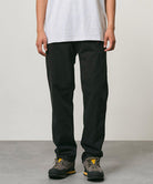 Model wearing black Gramicci Pants and a white shirt on a light-tone background.