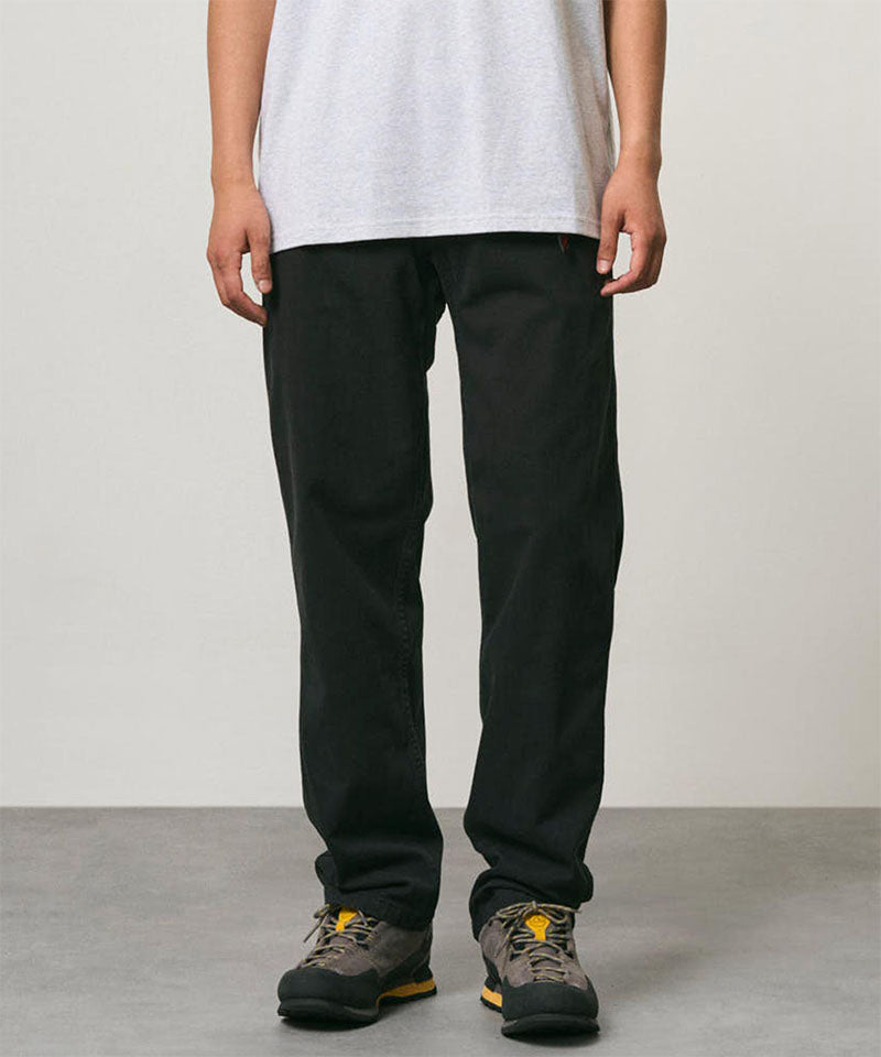 Model wearing black Gramicci Pants and a white shirt on a light-tone background.