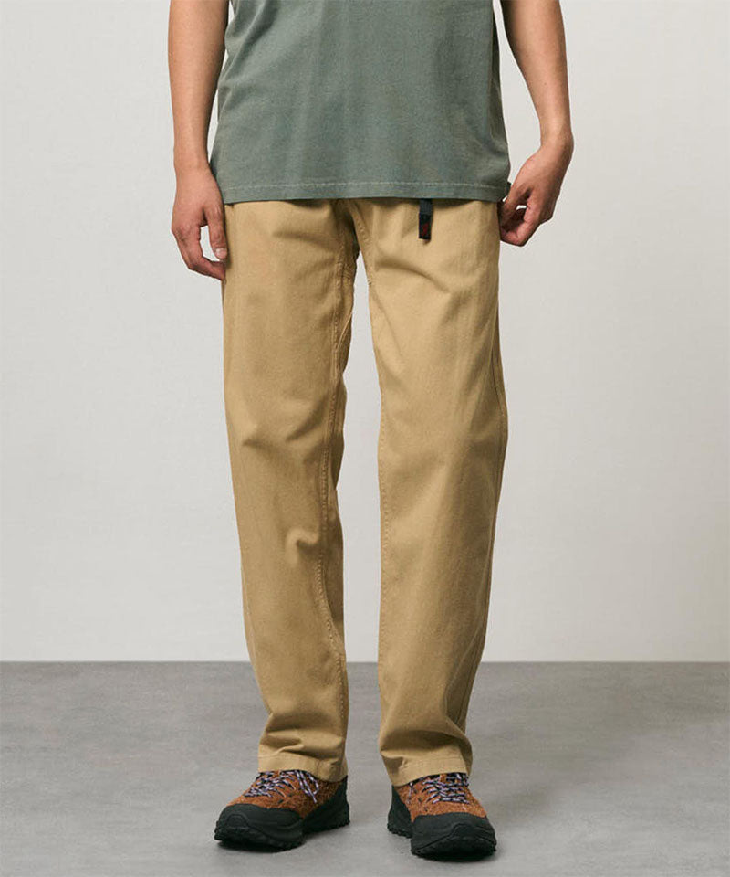 Model wearing chino colored Gramicci Pants and a olive shirt on a light-tone background.