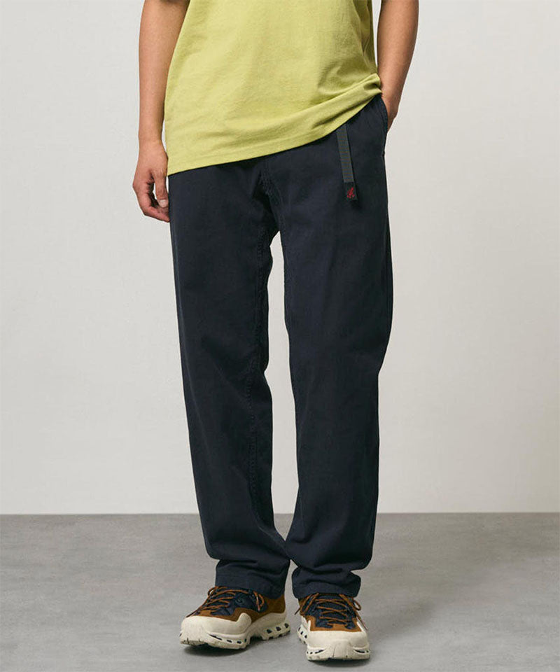 Model wearing double navy Gramicci Pants and a lime colored shirt on a light-tone background.