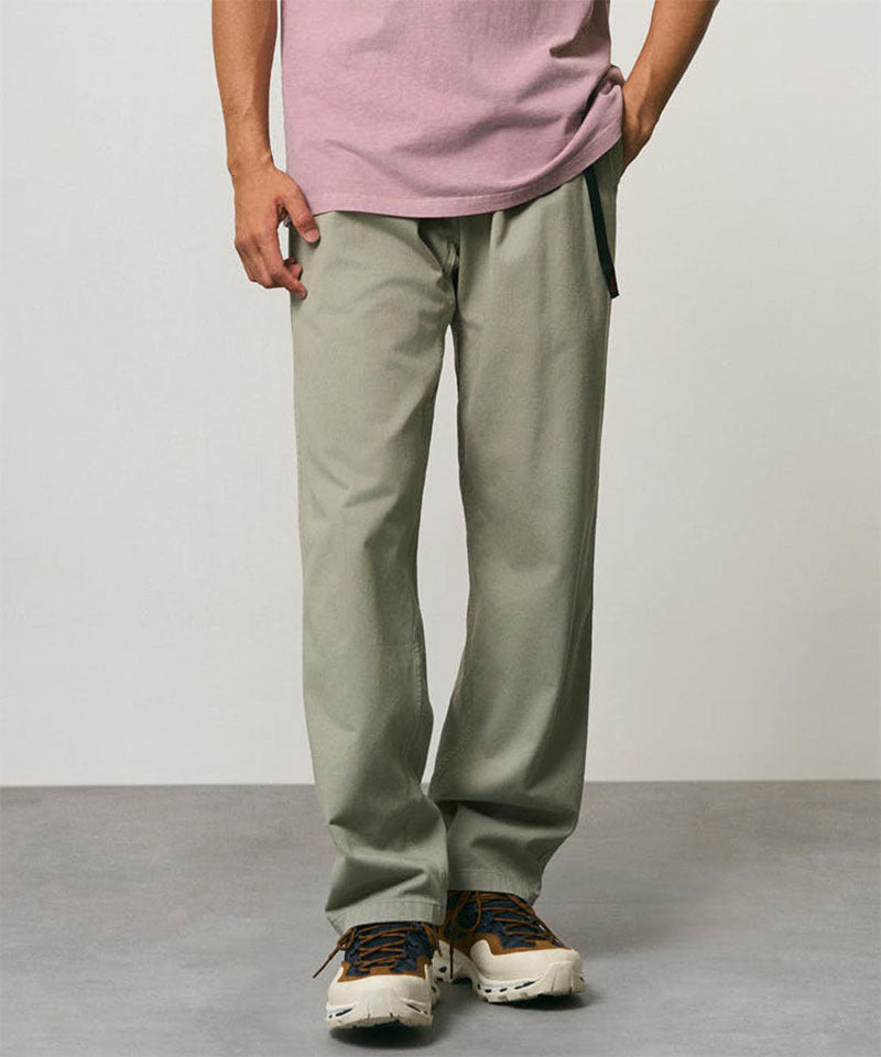 Model wearing dried sage colored Gramicci Pants and a dusty pink shirt on a light-tone background.