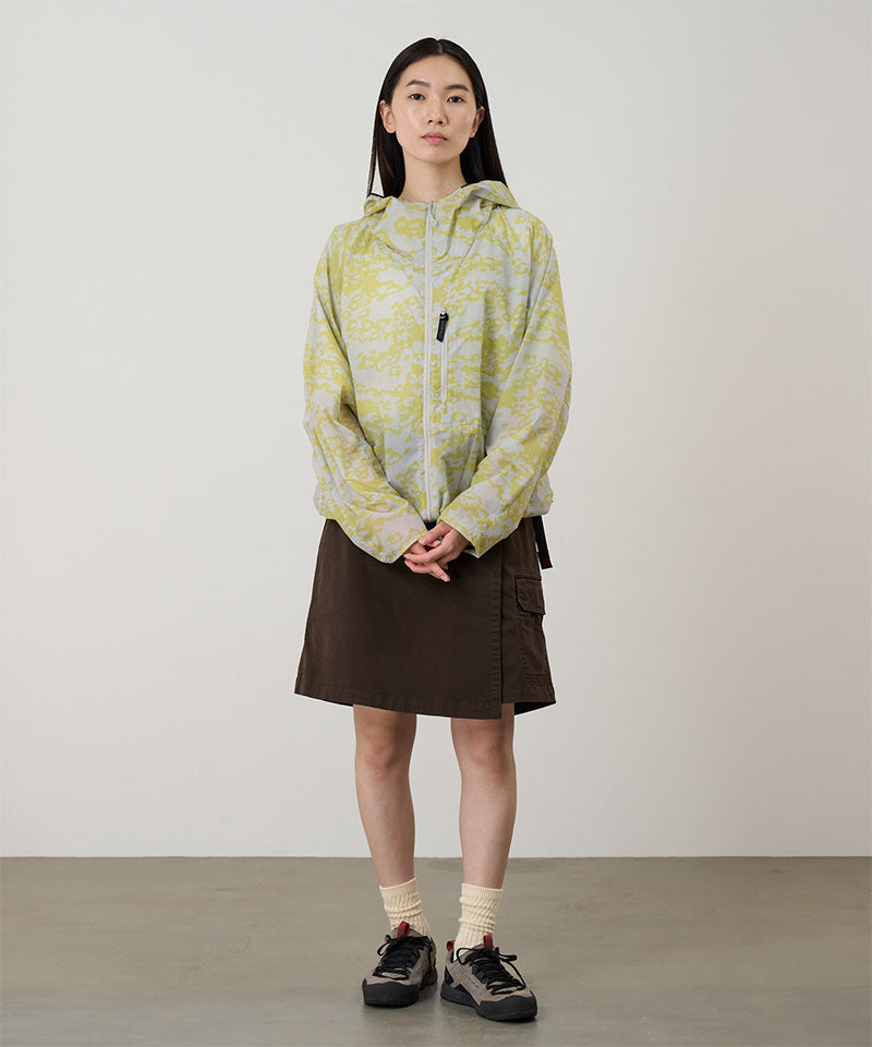 Model wearing a Gramicci G-Skort in the color chocolate and a yellow patterned jacket on a light-tone background.