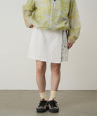 Model wearing a Gramicci G-Skort in the color shell white and a yellow patterned jacket on a light-tone background.