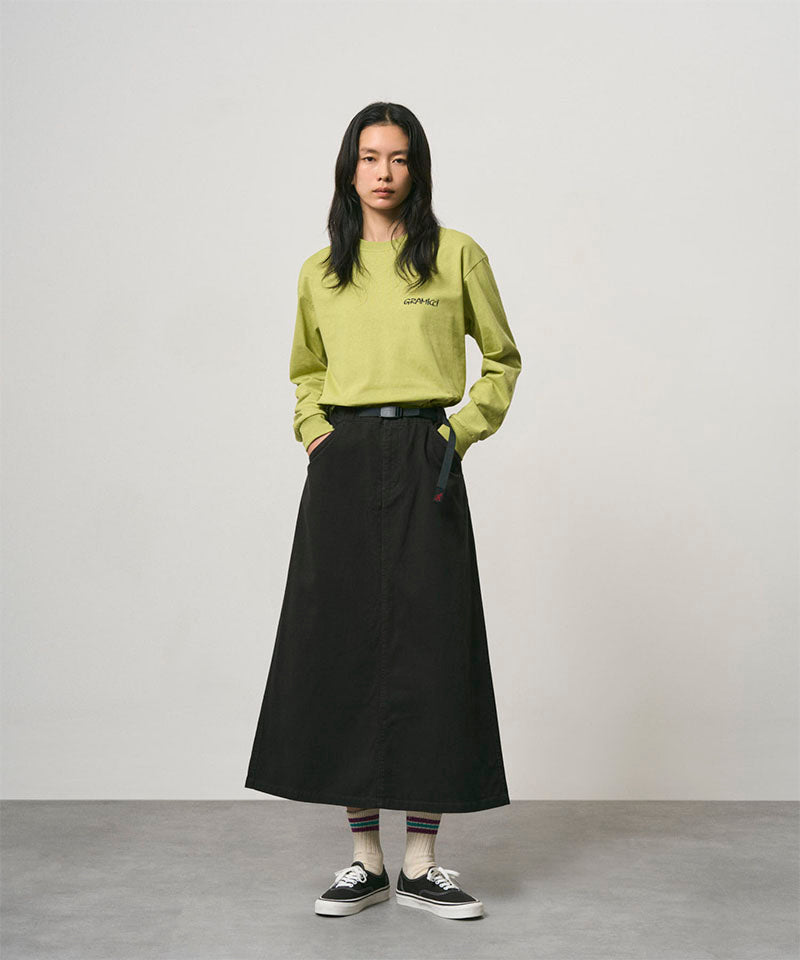 Model wearing a sweet pea colored Gramicci Bass Long-Sleeve Tee and black skirt on a light-tone background.