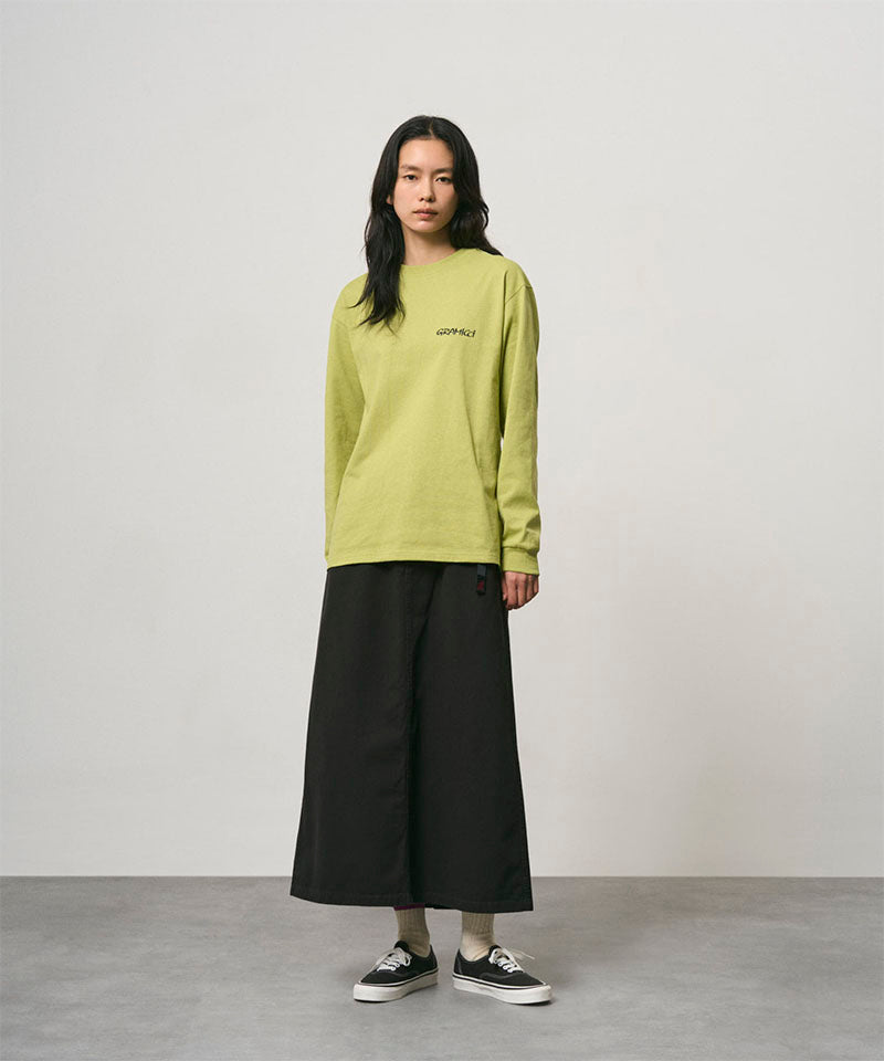 Model wearing a sweet pea colored Gramicci Bass Long-Sleeve Tee and black skirt on a light-tone background.