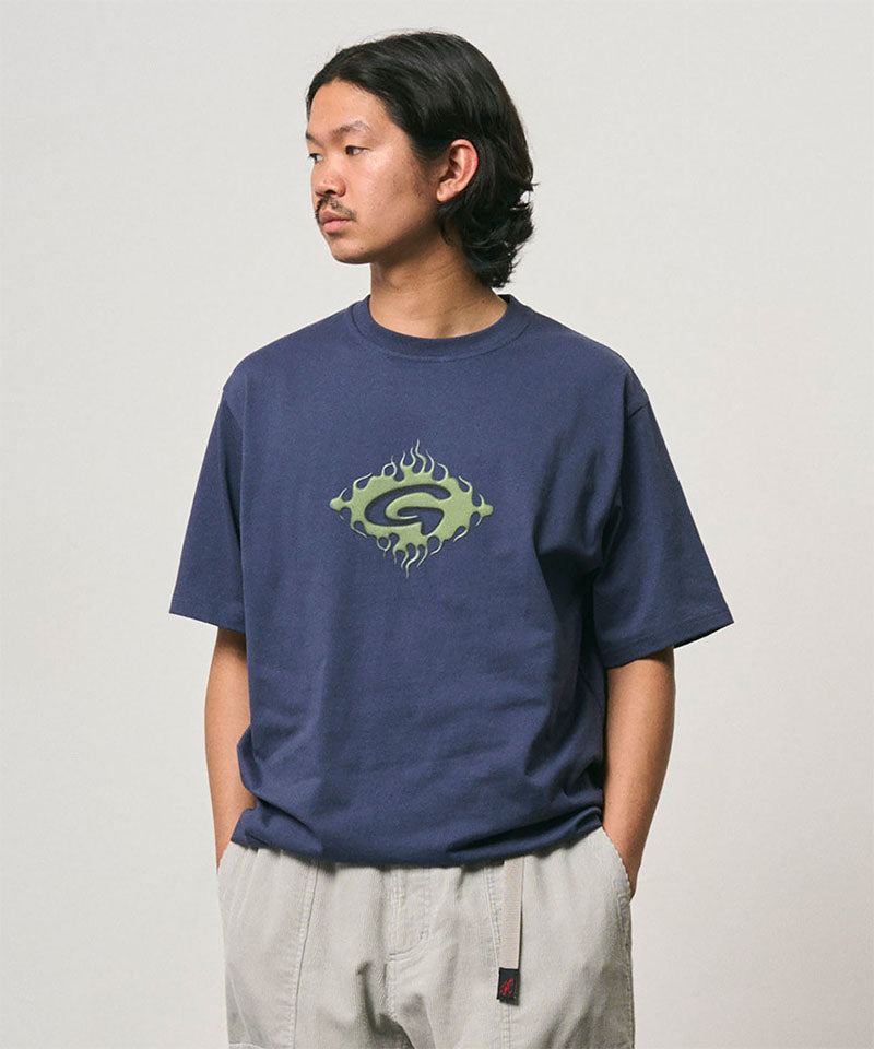 Model wearing a Gramicci navy Flames Tee with a graphic against a light-tone background.