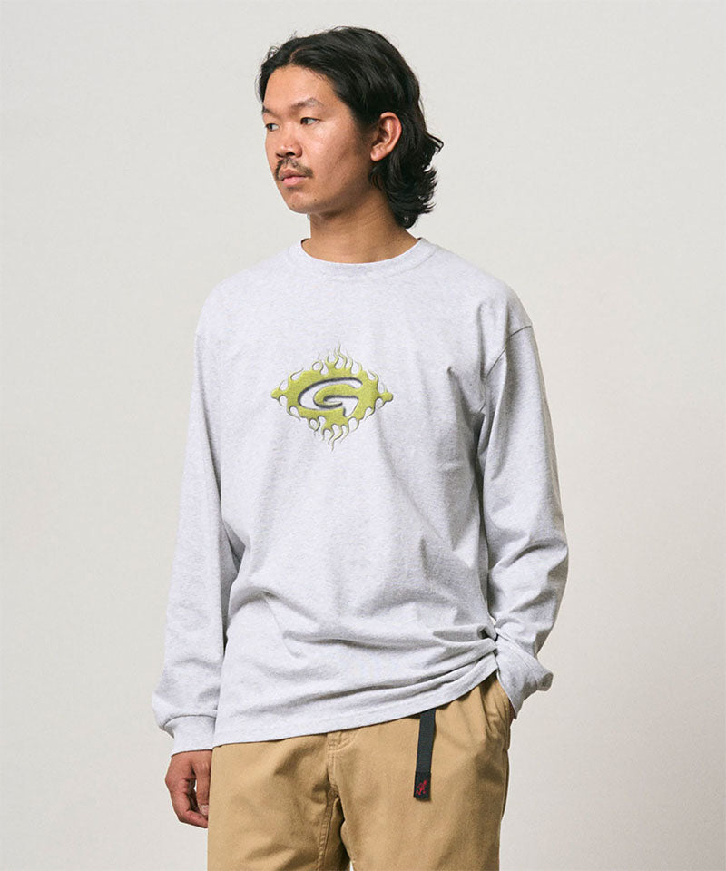 Model wearing a Gramicci ash heather colored Flames Long Sleeve Tee with a graphic against a light-tone background.