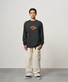 Model wearing a vintage black Gramicci Flames Long Sleeve Tee with a graphic and creme colored pants on a light-tone background.