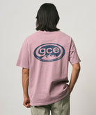 Model wearing a Gramicci lilac pigment colored GCE Tee Pigment Dyed with a graphic against a light-tone background.