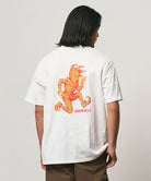 Model wearing a Gramicci white Joker Tee with an orange graphic against a light-tone background.