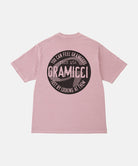 Back view of a Gramicci lilac pigment colored Icon Tee Pigment Dyed with a graphic against a light-tone background.