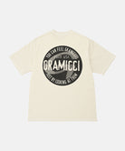 Back view of a Gramicci natural pigment colored Icon Tee Pigment Dyed with a graphic against a light-tone background.