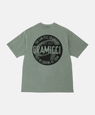 Back view of a Gramicci sage pigment colored Icon Tee Pigment Dyed with a graphic against a light-tone background.