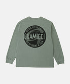 Back view of a Gramicci sage pigment colored Icon Long Sleeve Tee Pigment Dyed with a graphic against a light-tone background.