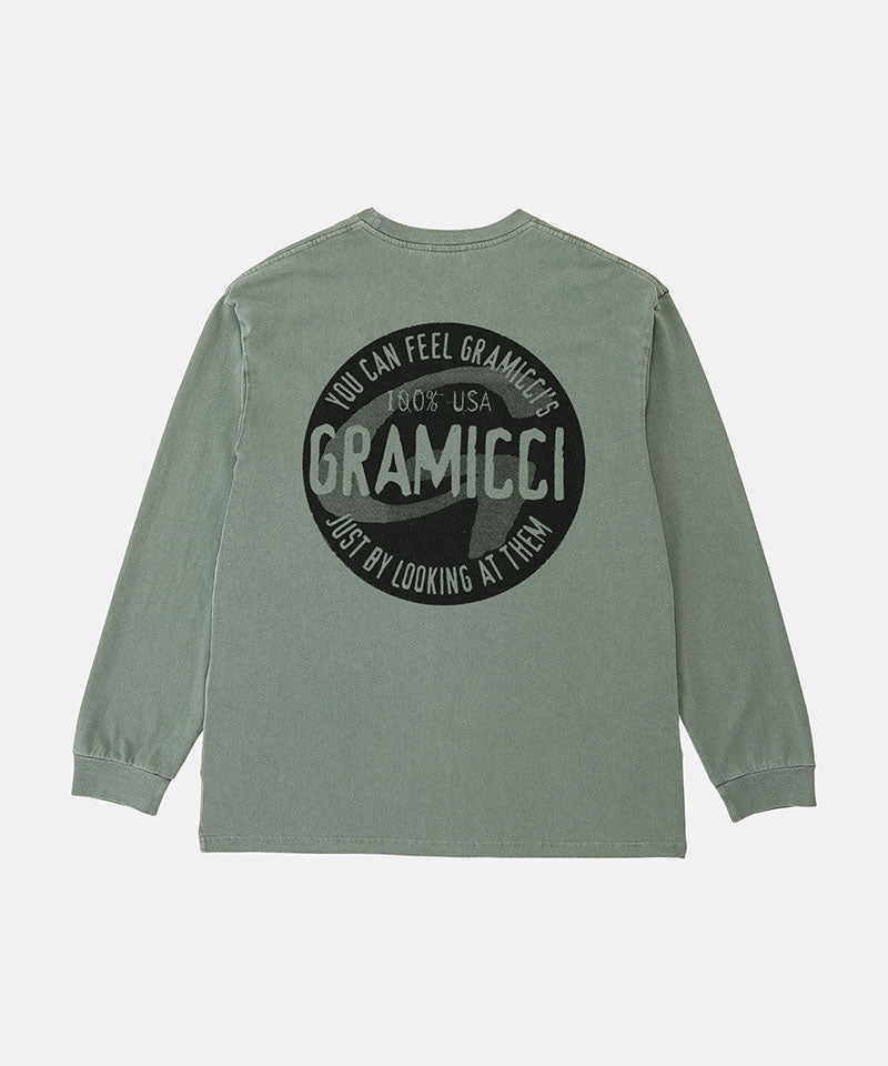 Back view of a Gramicci sage pigment colored Icon Long Sleeve Tee Pigment Dyed with a graphic against a light-tone background.