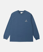 Model wearing a Gramicci dusky blue One Point Logo Long Sleeve Tee with a graphic against a light-tone background.