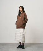 Model wearing a frost colored Gramicci G-Zero Primaloft Skirt and a brown hoodie on a light-tone background.