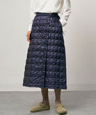 Model wearing a indigo Gramicci G-Zero Primaloft Skirt and a white shirt on a light-tone background.