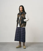 Model wearing a indigo Gramicci G-Zero Primaloft Skirt and a black and brown camo vest on a light-tone background.