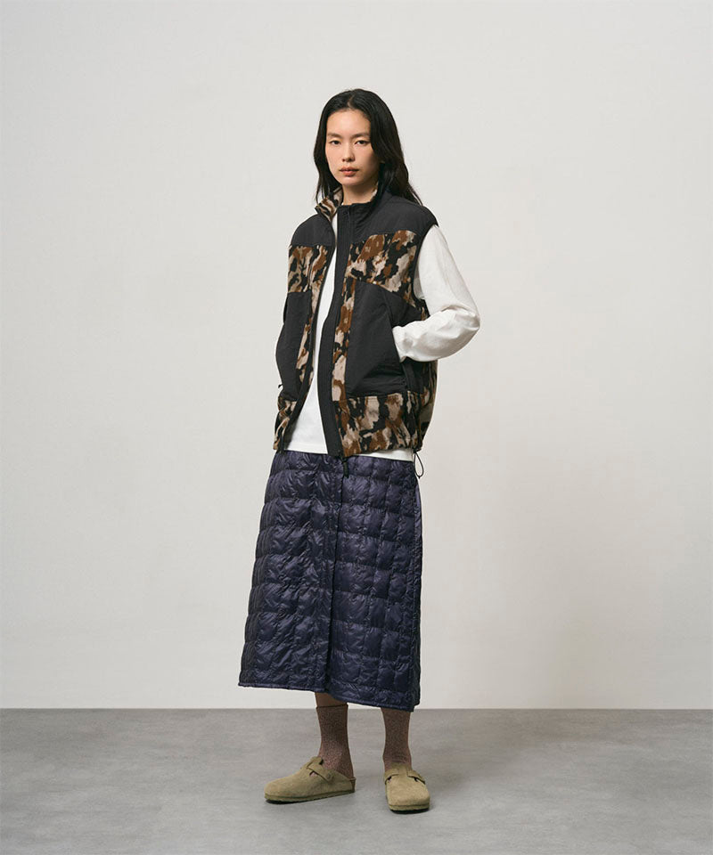Model wearing a indigo Gramicci G-Zero Primaloft Skirt and a black and brown camo vest on a light-tone background.