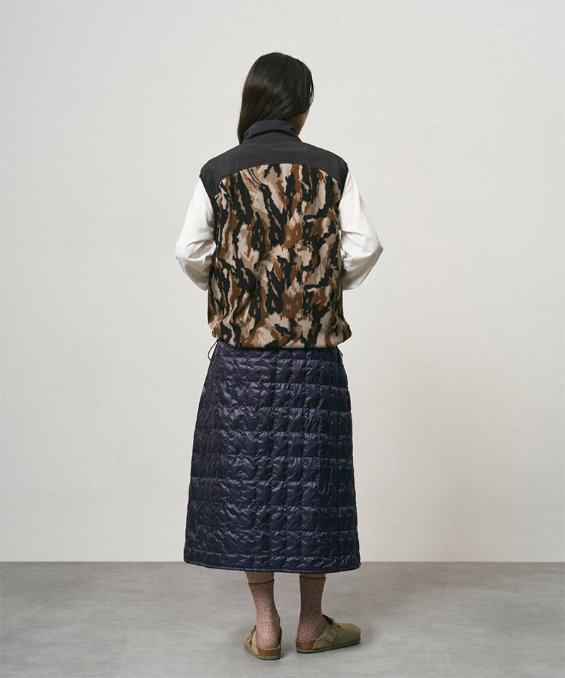 Model wearing a indigo Gramicci G-Zero Primaloft Skirt and a black and brown camo vest on a light-tone background.