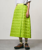 Model wearing a lime colored Gramicci G-Zero Primaloft Skirt and a white shirt on a light-tone background.