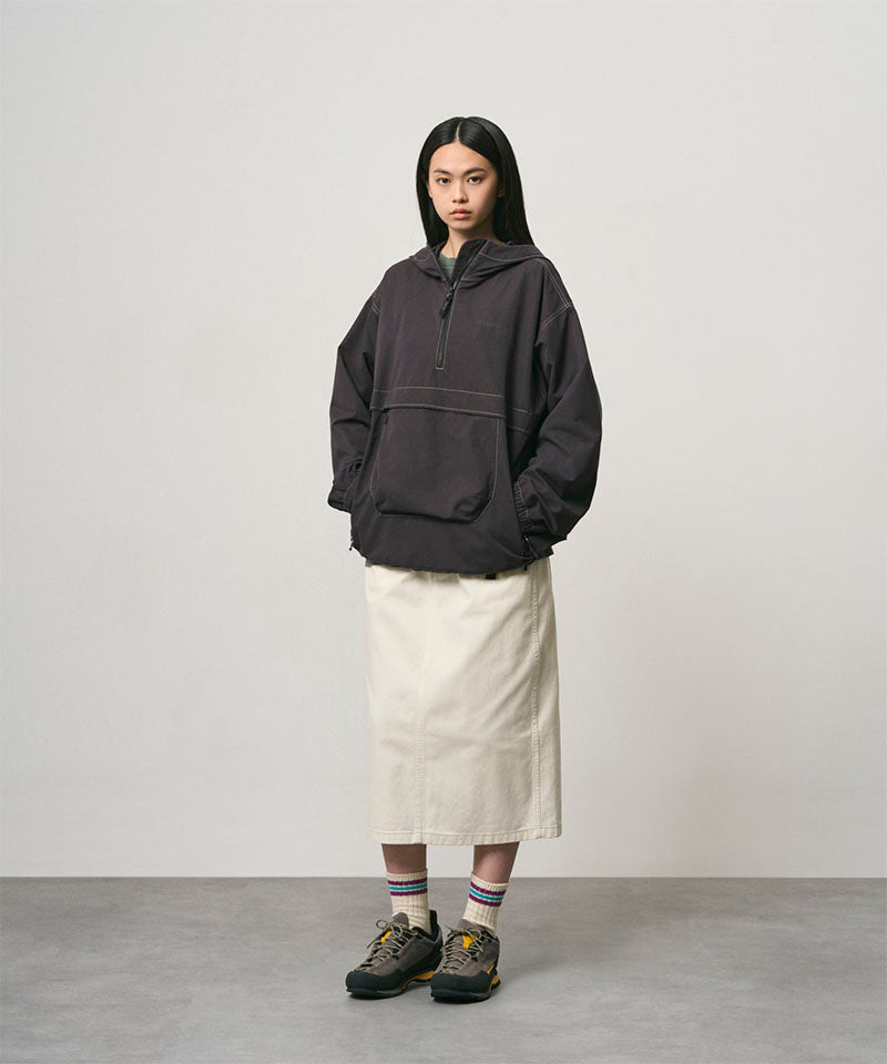 Model wearing a bone colored Gramicci Denim Carpenter Skirt and a dark brown jacket on a light-tone background.