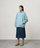 Model wearing a rinsed indego Gramicci Denim Carpenter Skirt and a light blue hoodie on a light-tone background.