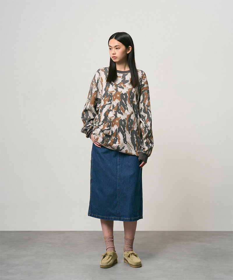Model wearing a stone colored Gramicci Denim Carpenter Skirt and a camo sweatshirt on a light-tone background.